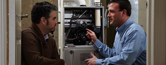 Technician answering costumer's questions during furnace repair