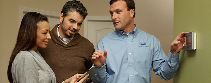 Technician demonstrating mobile device Smart Controls during furnace repair