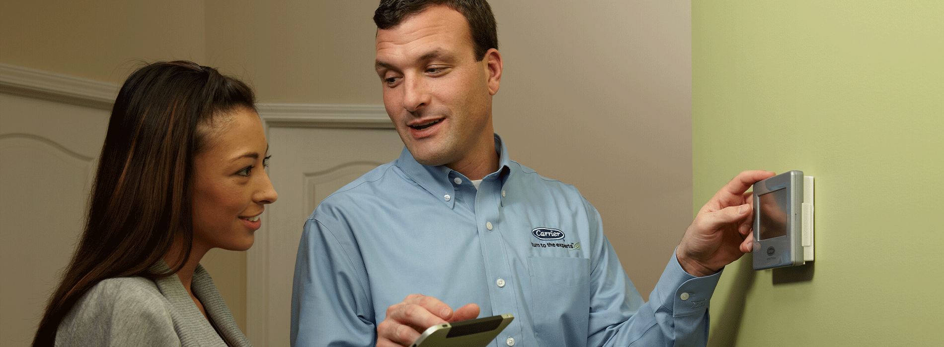 Technician showing costumer thermostat settings after HVAC replacement